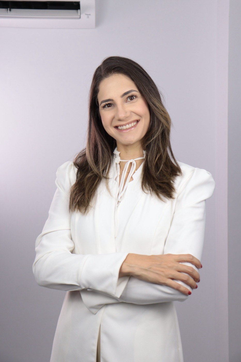 Dra. Stella Meireles, dermatologista, sorrindo de braços cruzados